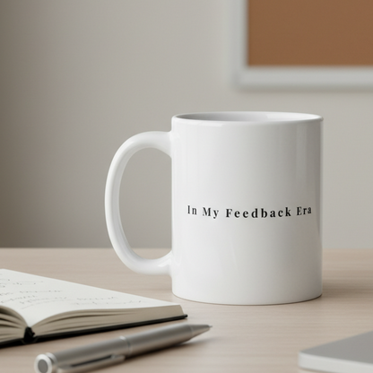 White mug with text on a desk with a notebook and pen